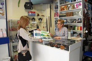 Lourdes Ramos muestra el cartel sobre recoclaje a una comerciante.tyle>.apqj{position:abso