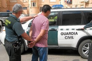 Un agente conduce al coche patrulla a uno de los detenidos. e;c