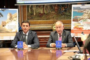 Javier Aureliano García y Gabriel Amat junto a los carteles promocionales.tyle>.apqj{posit