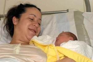 Una madre en una cama hospitalaria, tras dar a luz a su hijo. e