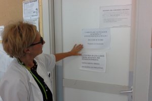 Una sanitaria indica uno de los carteles que anuncian la vacunación.