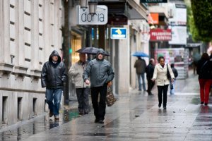 Unos ciudadanos caminan por el centro de la ciudad en una fria jornada de lluvia