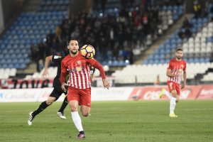 Quique mira la pelota y Puertas corre a su lado hacia el área.