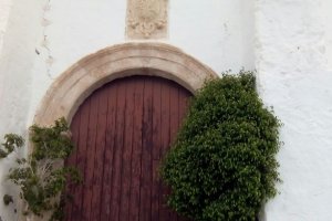 Flores y velas dejadas por vecinos, ante la puerta cerrada de la iglesia de Huebro.