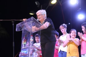 Josefa López, aplaudida por sus nietos, durante la lectura del pregón en Terreros.
