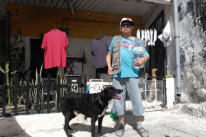 Edgard, vecino de La Alquería desde hace 30 años, junto a la puerta de su casa con una garrafa de agua.