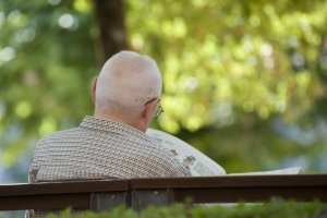 Una persona mayor descansa mientras lee la prensa en un parque de la ciudad.