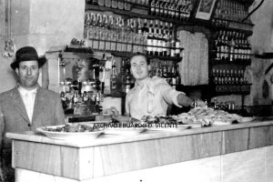 josé Murcia Moya, fundador y dueño del bar ‘El Cuco’, aparece detrás del mostrador con un sombrero oscuro en una imagen de 1945. A su lado está su hi