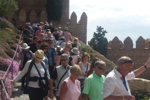Visitantes bajan del conjunto monumental conducidos por un guía turístico.