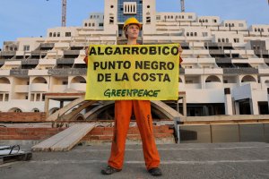 Una activista de Greenpeace porta una pancarta de protesta frente al hotel de El Algarrobico.