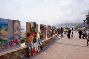 La gente recorre el Paseo Marítimo de Mojácar admirando el trabajo de los pintores.