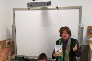 Clementina y su nieto posan frente a la pizarra y con el cuento solidario.