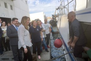 Susana Díaz y un pescador se saludan con el mar y las boyas de por medio en la tarde de ayer.