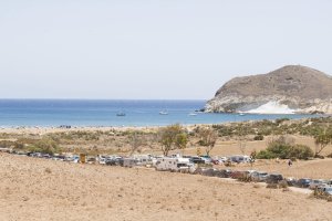 Camino de acceso al aparcamiento de Genoveses, con vehículos en los lados.
