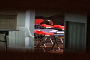 Inmigrantes en camillas en el frontón, en una imagen tomada la noche del sábado desde el exterior del recinto deportivo.