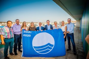 Autoridades autonómicas y municipales con la bandera azul que se ha izado en el Puerto de Roquetas.
