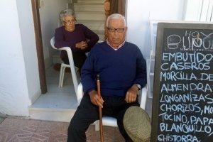 Ginés Gallardo y su mujer Luisa Nájar, con la pizarra de la tienda, junto a la fuente de Mojácar.