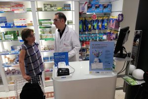 Un farmacéutico atiende a una cliente en una farmacia.
