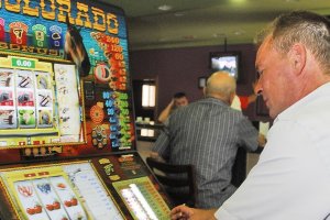 Un hombre juega a la máquina tragaperras en un salón de juego.