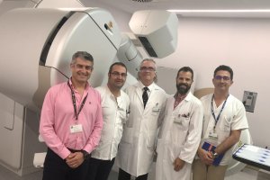 El gerente y profesionales del hospital junto al acelerador donado.