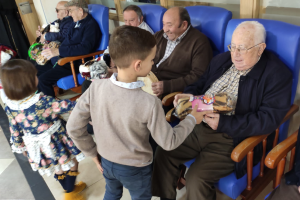 Un niño entrega un regalo a un anciano.