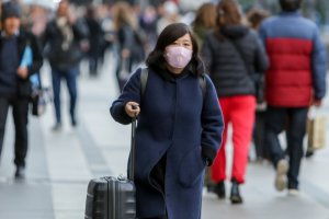 Una mujer de origen asiático camina con una mascarilla por las calles de Madrid.