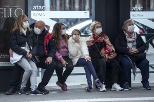 Gente con mascarillas en una parada de autobús de Roma.