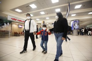 Una familia con mascarillas en el aeropuerto Mariscal Sucre.