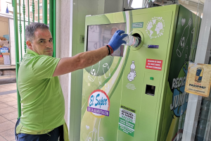 Víctor Martínez, propietario de El Súper de El Alquián, introduce una botella en el contenedor para reciclaje.