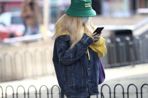 Una mujer con una mascarilla y un teléfono en mano.