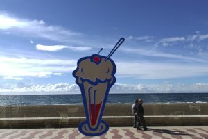 Paseo Marítimo de Almería visto al otro lado de la cristalera de una heladería.