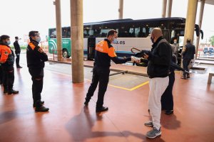 Imagen de un agente de protección civil entregando una mascarilla a un pasajero.