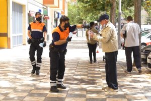 Un miembro de Protección Civil entrega una mascarilla a un transeúnte en la Avenida Rey Juan Carlos.
