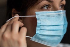 Una mujer se pone una mascarilla.