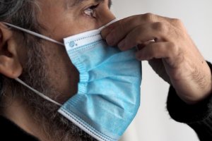 Un hombre se pone una mascarilla.