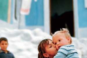 Una niña del barrio de las cuevas de la Alcazaba llevando en brazos y besando a su hermano pequeño.