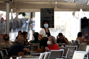Una camarera con mascarilla atiende a los clientes en una terraza de un bar de Madrid.