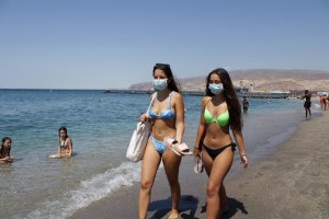 Jóvenes almerienses con mascarilla en la playa.