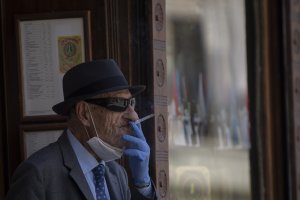 Un hombre con mascarilla y guantes fumando un cigarro en Sevilla.