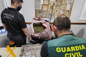 Un agente de la Guardia Civil y la Policía Local con parte del material incautado.