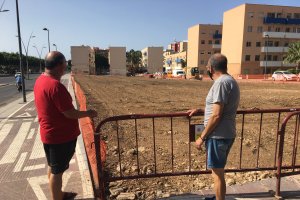 Dos almerienses miran unas obras junto a la Avenida del Mediterráneo este pasado verano.