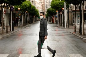 Un hombre con mascarilla recorre una vacía calle de Murcia.