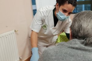 Una residente en un geriátrico atendida por una profesional con mascarilla.