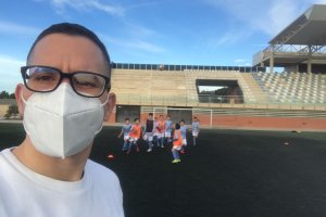 El entrenador en primer plano y sus futbolistas de fondo.