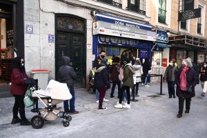Varias personas hacen cola ante la administración de lotería Doña Manolita, en Madrid.