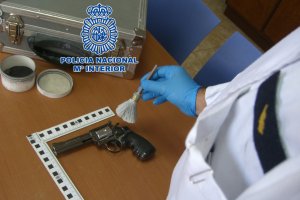 Un agente analizando huellas en un arma.