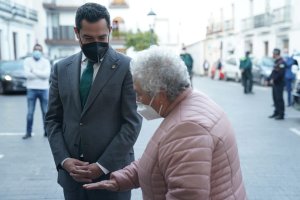 Juanma Moreno charla con una mujer, ambos con la mascarilla puesta, en una imagen de archivo.