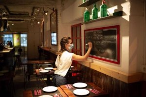 Una camarera apunta platos en una pizarra en el interior de un bar.