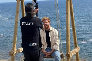 Juanlu González graba sentado en el columpio instalado en Cala Invencible.