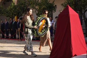 La alumna Ana Segura coloca la corona de flores junto a su profesora